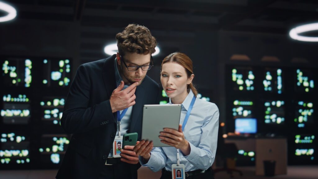 Man woman server technicians working pad computer in night data center closeup