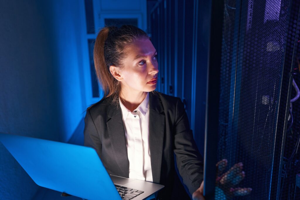 Professional young woman working in server room